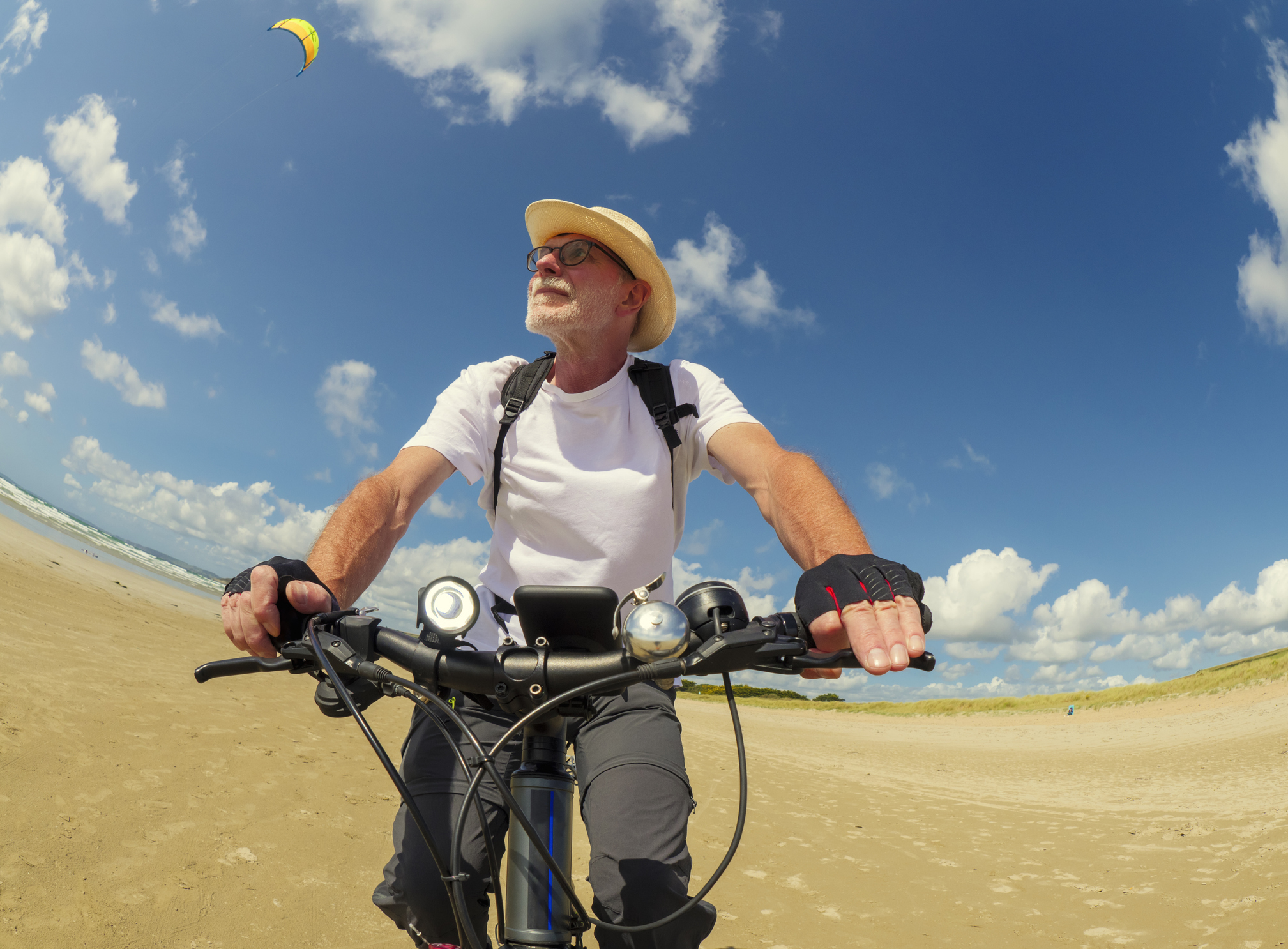 Homme sur un vélo sur la plage avec un chapeau de paille